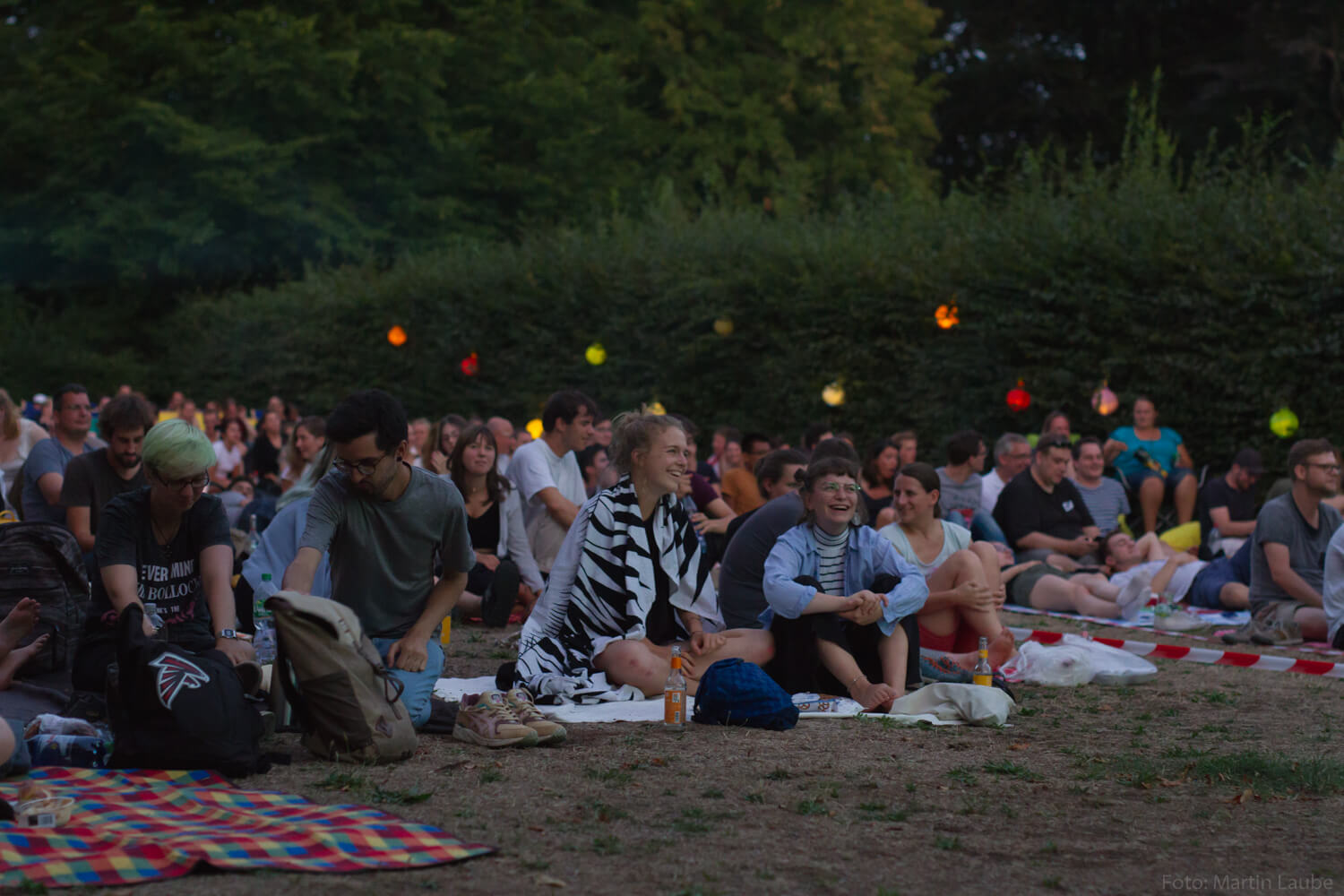 Publikum auf Picknickdecken vor der Leinwand