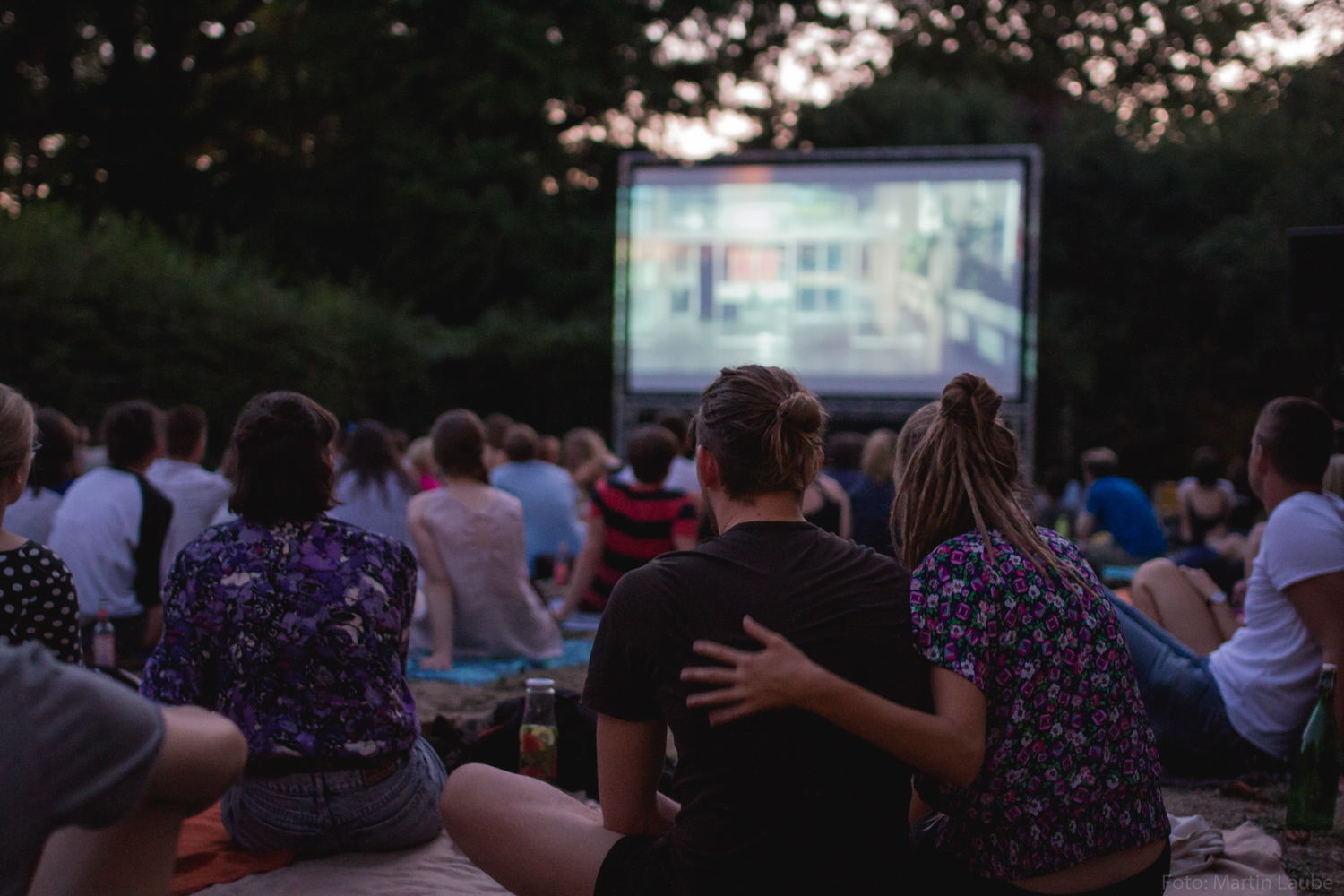 Publikum auf Picknickdecken vor der Leinwand