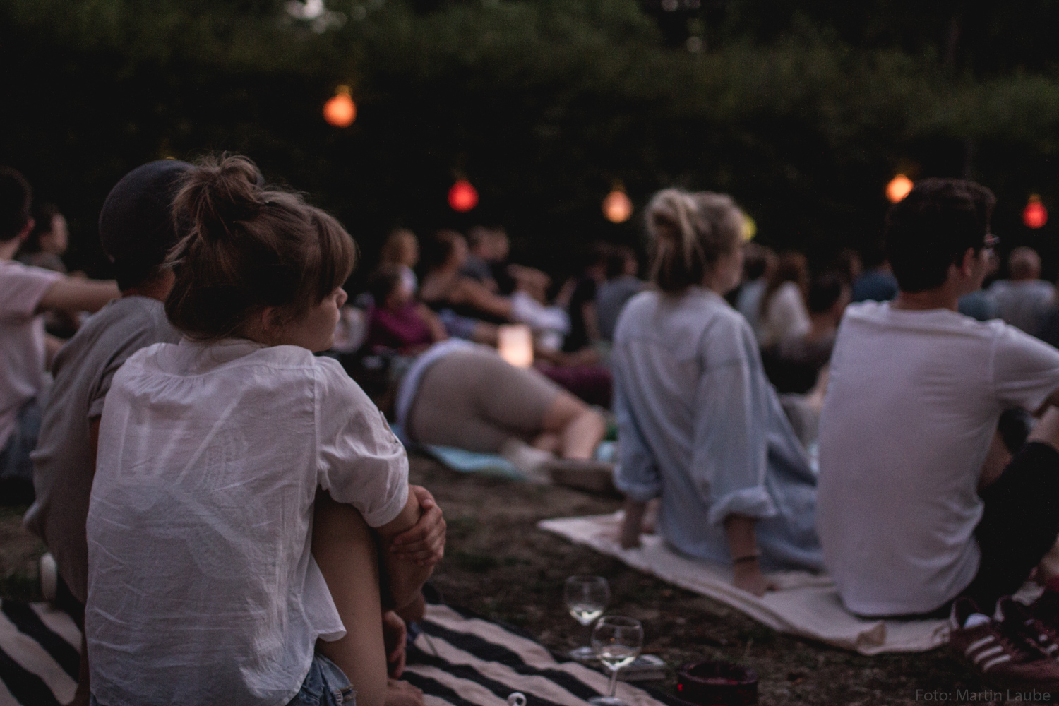 Publikum auf Picknickdecken vor der Leinwand